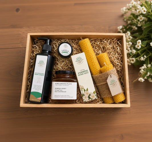 Organiks Plus Natural Wellness Gift Pack set with skincare products and candles in a wooden box on a wooden surface.