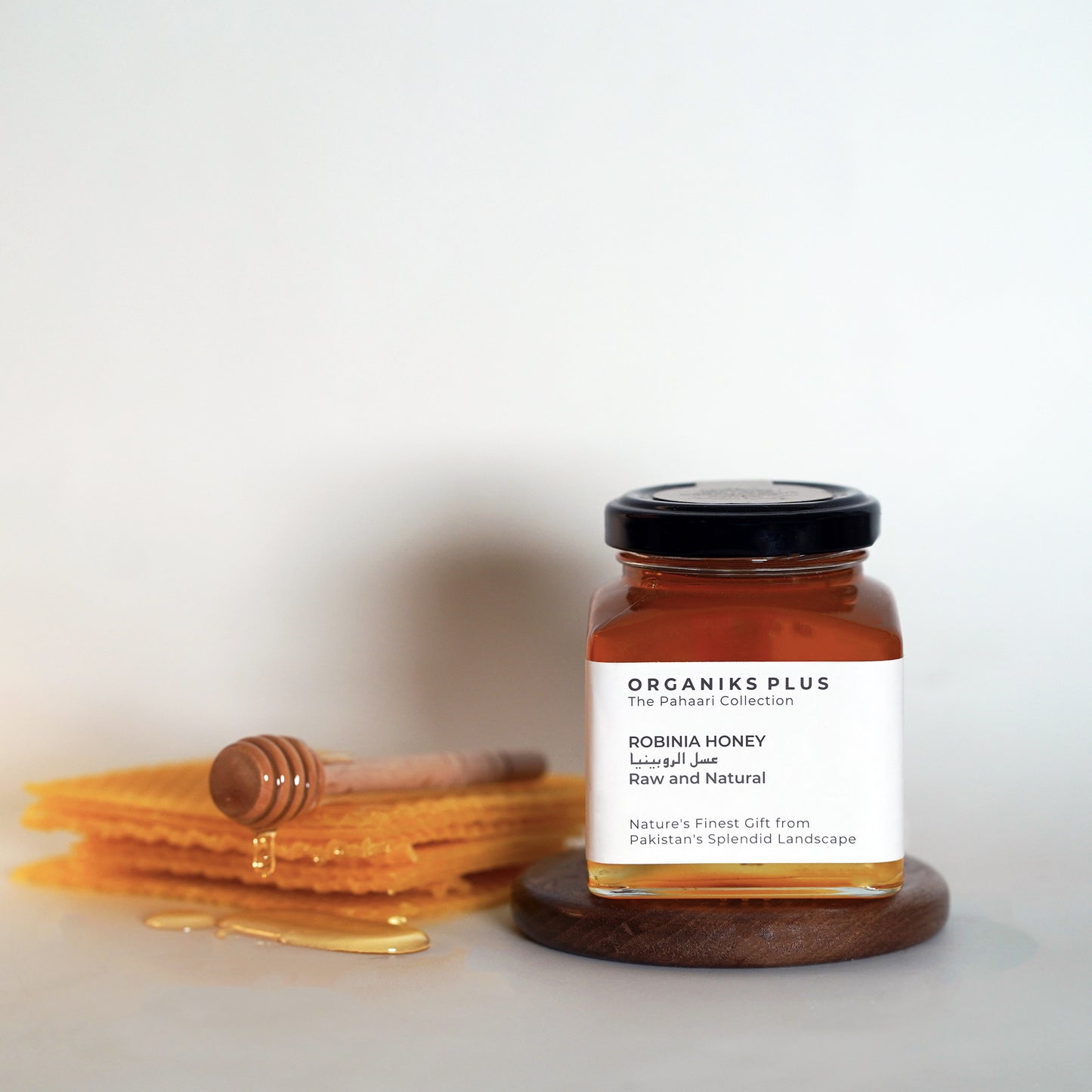 Jar of Organiks Plus Robina Honey with honey comb on a white background
