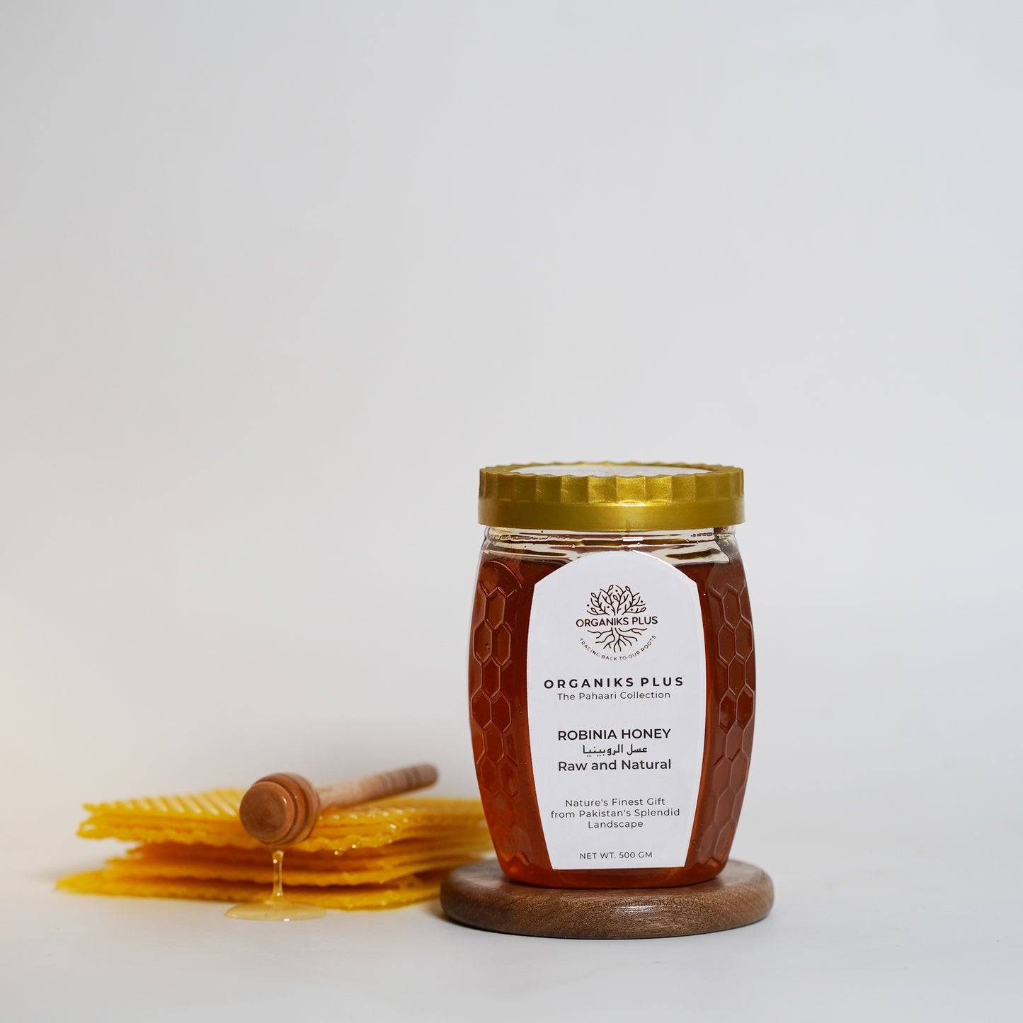 Jar of honey with a honey dipper on a white background