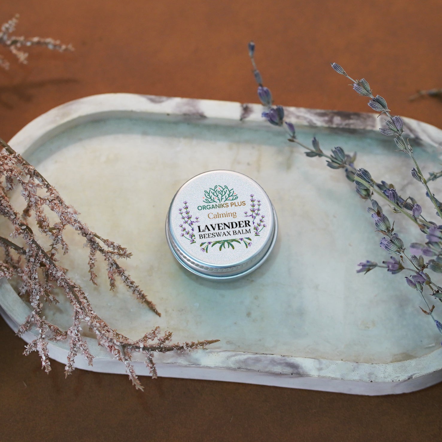 Lavender beeswax balm tin on a decorative stone surface with lavender sprigs.