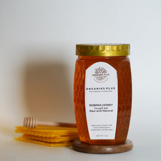Jar of Organiks Plus Robina Honey on a wooden stand with a blurred background. 