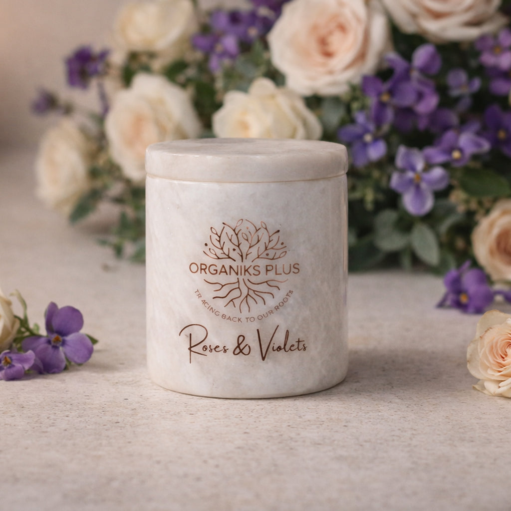 Marble Candle jar labeled 'Organiks Plus Roses & Violets' with flowers in the background
