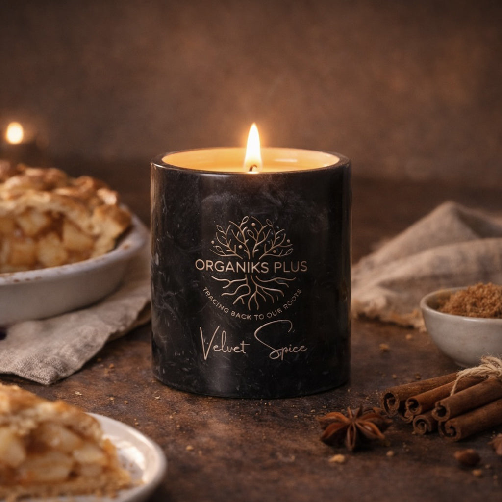 Candle with 'Organiks Plus' branding on a rustic surface with spices and pastries.