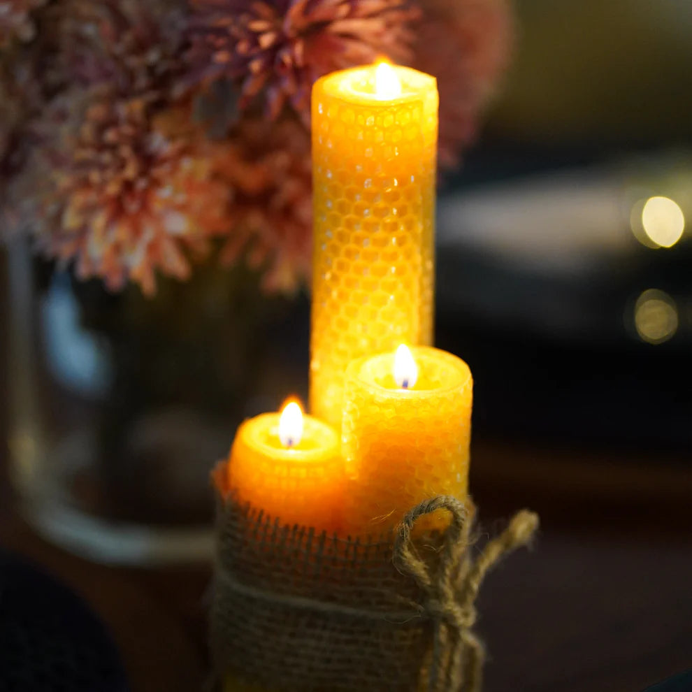 Pure beeswax taper candles burning with soft golden light and natural honey fragrance.